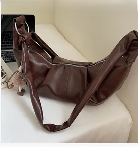 Detail of dark brown leather crescent bag with top handle and soft plush charm accessory