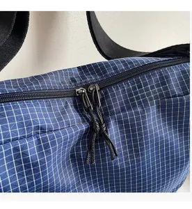 Detail view of smooth double zippers on a blue checkered canvas tote shoulder bag