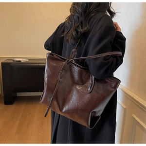 Detail of dark brown glossy oil wax leather tote bag with vintage texture on a model