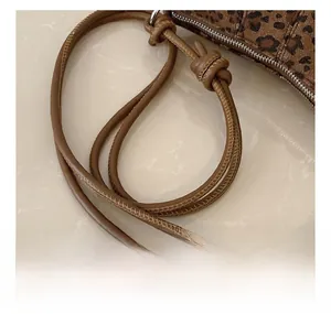 Dettaglio borsa leopardata con tracolla in pelle marrone annodata e cerniera in metallo