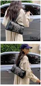 Close-up of black cylinder bag with silver studs worn as a stylish punk shoulder bag