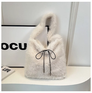 Détail d'un sac à main en peluche avec un nœud noir décoratif et une texture douce en fausse fourrure