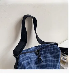 Detail of blue plaid canvas tote bag showing double zipper and durable black strap