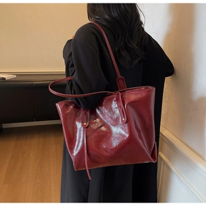 Detail view of burgundy glossy leather tote bag showing rich texture and slim shoulder straps