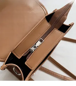 Detailed close-up of brown faux leather bag showing zipper closure and internal storage