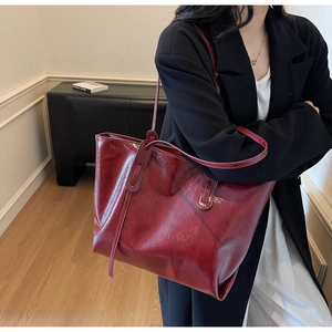 Detailed view of the glossy wine red leather tote bag with stylish shoulder strap