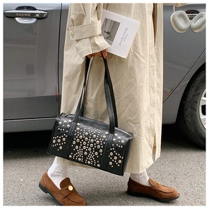 Street style shot of a black tote bag with silver studs and long shoulder straps