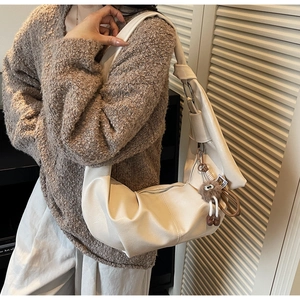 Detail of cream white half-moon shoulder bag in premium PU leather with plush charm