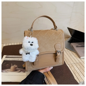 Detail of khaki leather bag with quilted flap, metal buckles and plush puppy charm