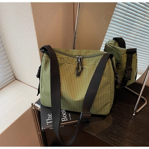 Detailed view of the green checkered canvas crossbody bag with black adjustable strap