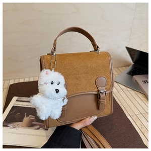 Detail of vintage brown quilted backpack featuring a Ninaite logo and white dog charm