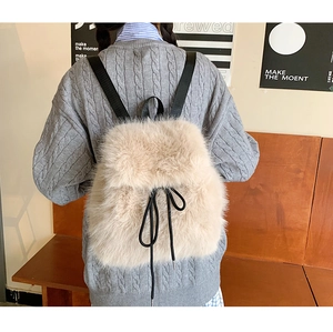 Detail of soft beige faux fur backpack featuring black ribbon drawstring and woven straps