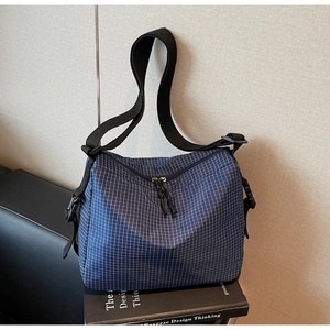 Detail of blue plaid canvas tote showing dual zippers and adjustable plastic side buckles