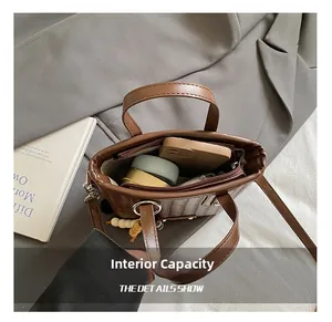 Détail montrant la capacité interne du sac tressé marron avec téléphone et maquillage