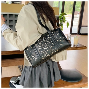 Close-up of black punk rivet handbag featuring silver studs on polished leather