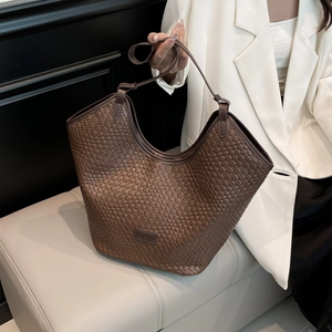 Dettaglio della borsa tote in pelle marrone scuro intrecciata a mano con trama fine e capienza