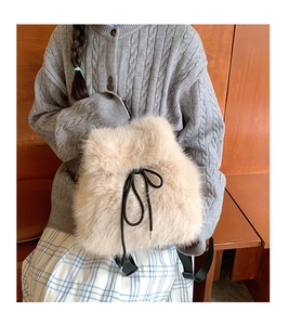 Cozy beige faux fur bucket backpack with black drawstring details on a grey sweater model