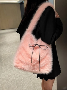 Sac fourre-tout rose en fausse fourrure avec nœud noir porté par un mannequin en costume