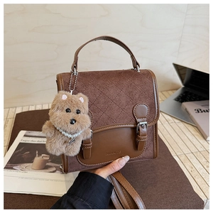 Close-up of brown vintage mini square bag with diamond stitching and cute bear charm