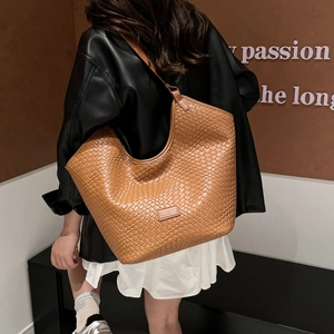 Dettaglio della borsa tote in pelle PU intrecciata marrone indossata da una modella