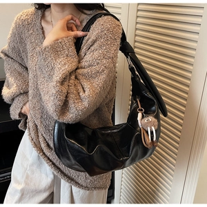 Detail of black large hobo bag featuring retro wrinkled texture and cute plush bear charm