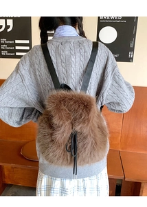 Rear view of a stylish brown faux fur backpack with black straps on a female model
