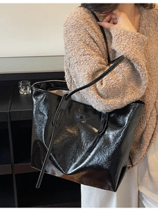Minimalist large black tote bag with wrinkled glossy finish and thin shoulder straps