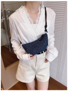 Dettaglio borsa a mezzaluna in denim blu con stampa leopardata scura e tracolla a nodo