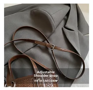 Détail de la bandoulière réglable et texture tressée du sac seau marron en similicuir