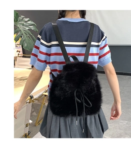 Detail shot of a black faux fur mini backpack with soft plush texture and drawstring close