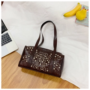 Close-up of dark brown studded shoulder bag with silver rivets on glossy leather