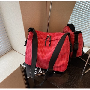 Detail of red plaid canvas bag with adjustable black strap and functional side buckle