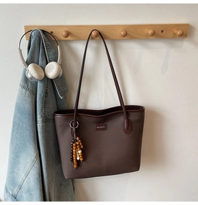 Detailansicht der braunen Tragetasche mit Holzperlen an einem Wandhaken aus Holz