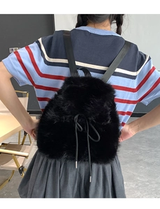 Close-up of black faux fur backpack with drawstring bow and textured plush material