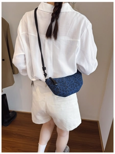 Dettaglio della borsa a mezzaluna in denim blu con stampa leopardata su abito bianco