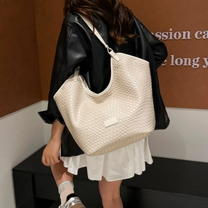 Dettaglio della trama intrecciata bianco crema e del logo in pelle sulla borsa tote