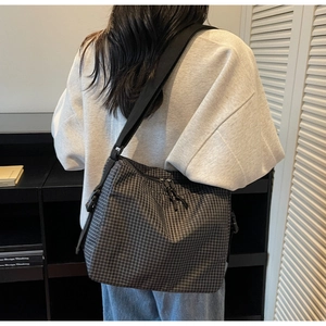 Detail view of plaid canvas crossbody bag with adjustable wide strap and dual zippers