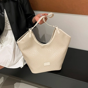 Dettaglio della borsa tote crema minimalista con trama intrecciata e patch logo rettangolare