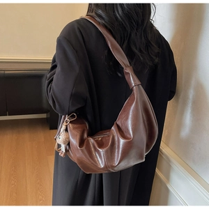 Detail view of large dark brown hobo shoulder bag with knot strap and plush pendant