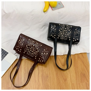 Top view of two studded cylinder shoulder bags in brown and black with silver rivets