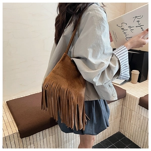 Detail of caramel suede shoulder bag showing long fringe tassels and premium texture