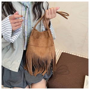Detail of dark camel suede bucket bag featuring long bohemian tassels and handles