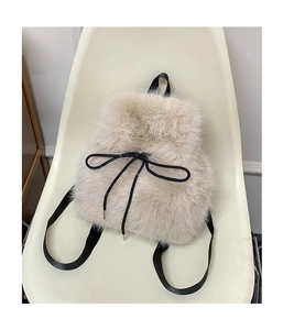 Detailed close-up of fuzzy cream faux fur backpack with black drawstring bow decoration
