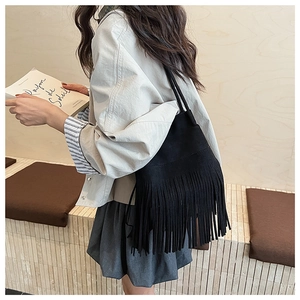 Close-up of black fringe bucket bag in matte suede texture with long tassel detail