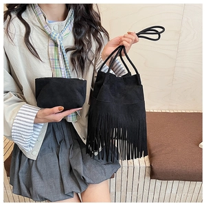 Detalle del bolso de ante negro con flecos, bolsa a juego y correa de cuerda trenzada