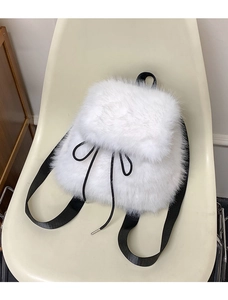 Detail of white faux fur backpack featuring black nylon drawstrings and metal tips