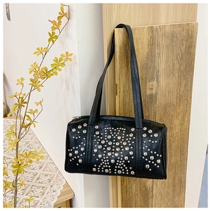 Detail of black PU leather pillow bag featuring silver punk rivets and zip closure