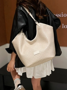 Grande borsa shopper intrecciata color crema indossata da una modella per look casual