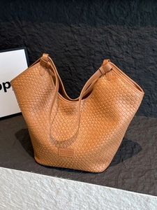 Borsa tote vintage in pelle intrecciata marrone con spalline lunghe su sfondo di pietra