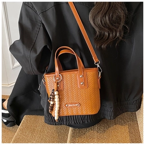 Détail du sac à main tissé orange-brun en cuir PU avec pendentif perlé et logo métal